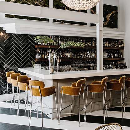 Modern art-deco inspired bar featuring black and brass details, a bold tiled floor and wall art of Einstein riding a bicycle