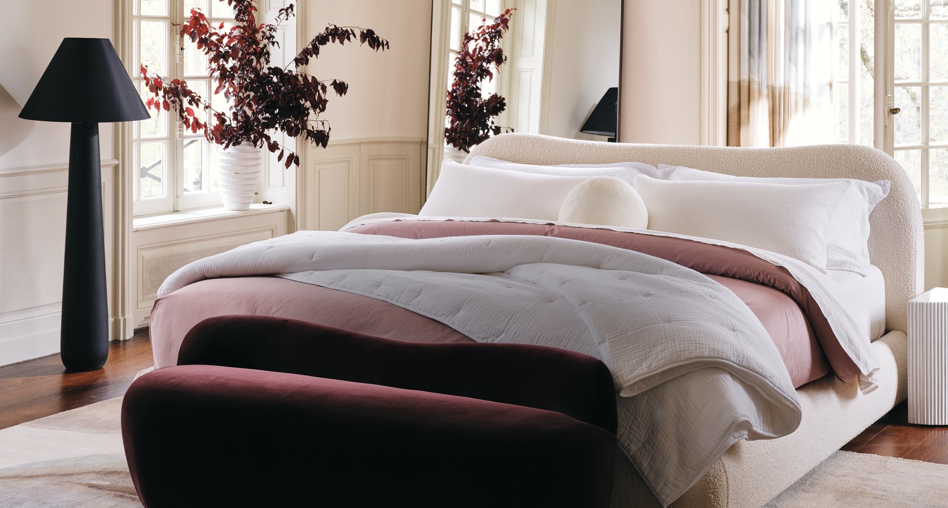 Modern White bed with red bedding and modern red cushioned bench at the foot of the bed