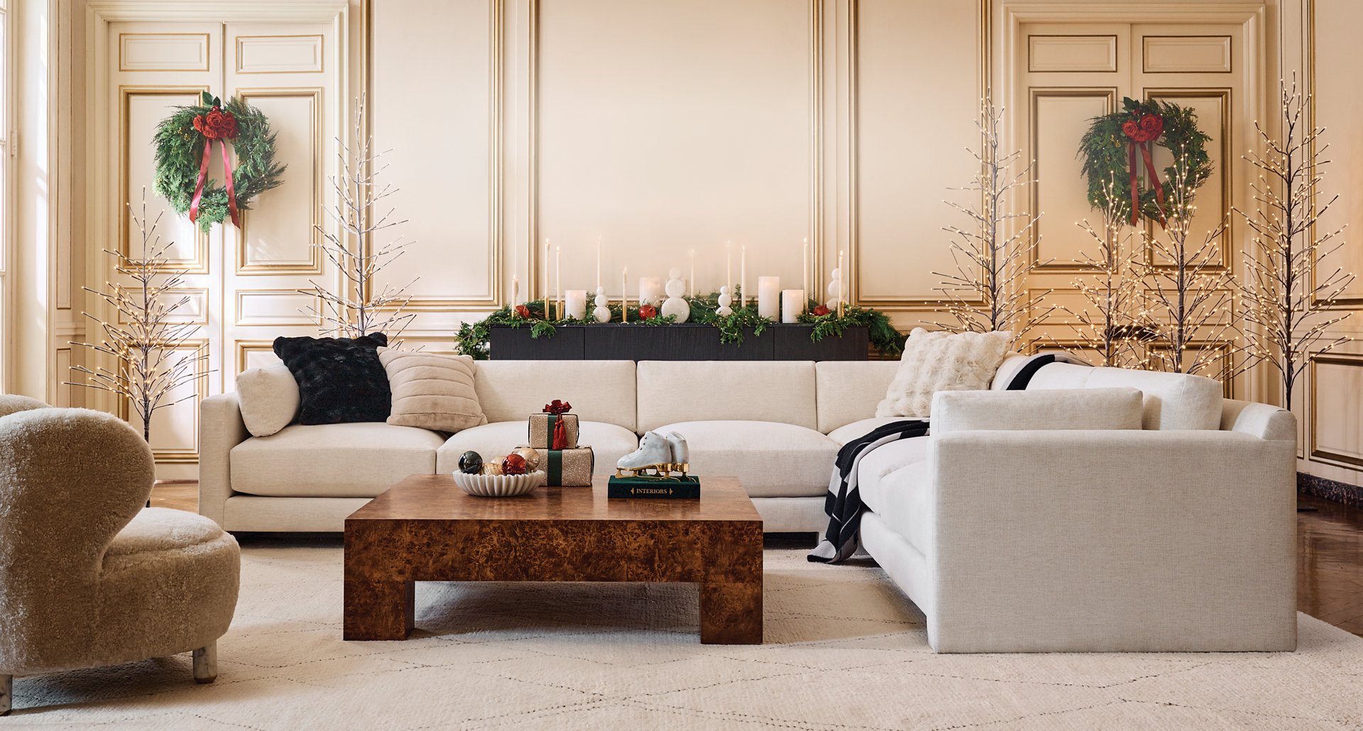 Living room with White Sectional, with large square wooden coffee table, Shearling Accent Chair and Holiday Decor