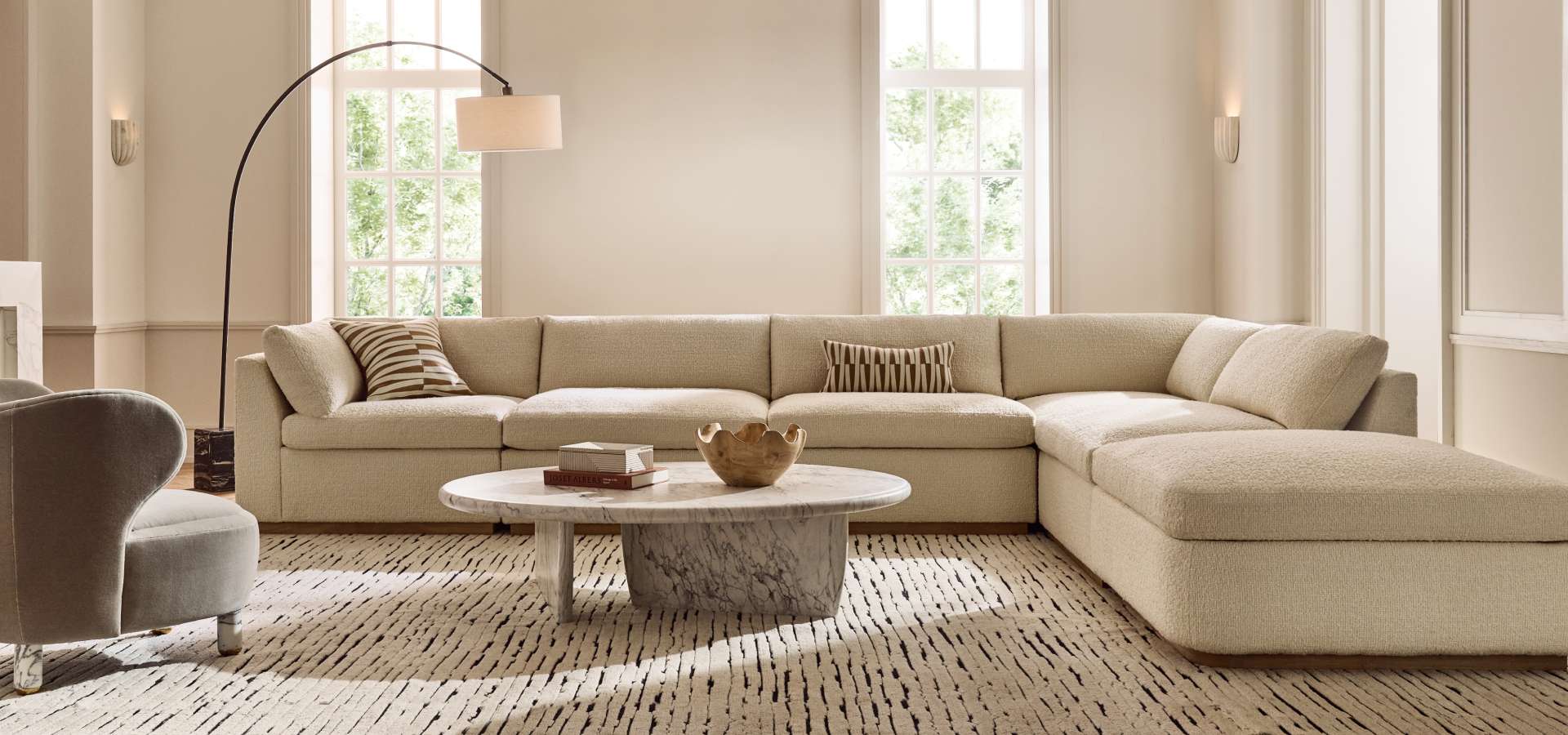 Large and spacious room with brown couch and white accent chair with a rug between them