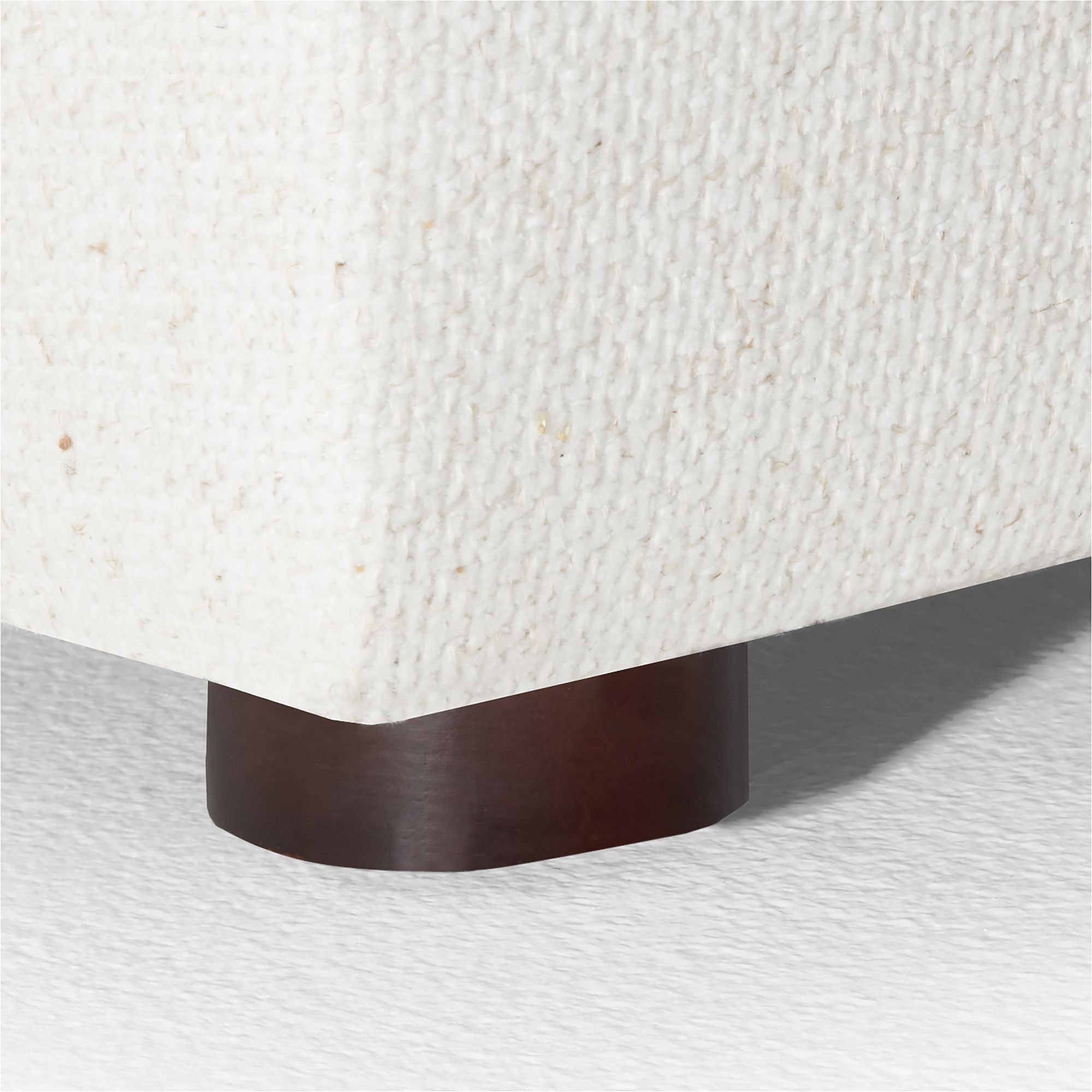 Close-up of the wooden base support of the white sleeper sofa.