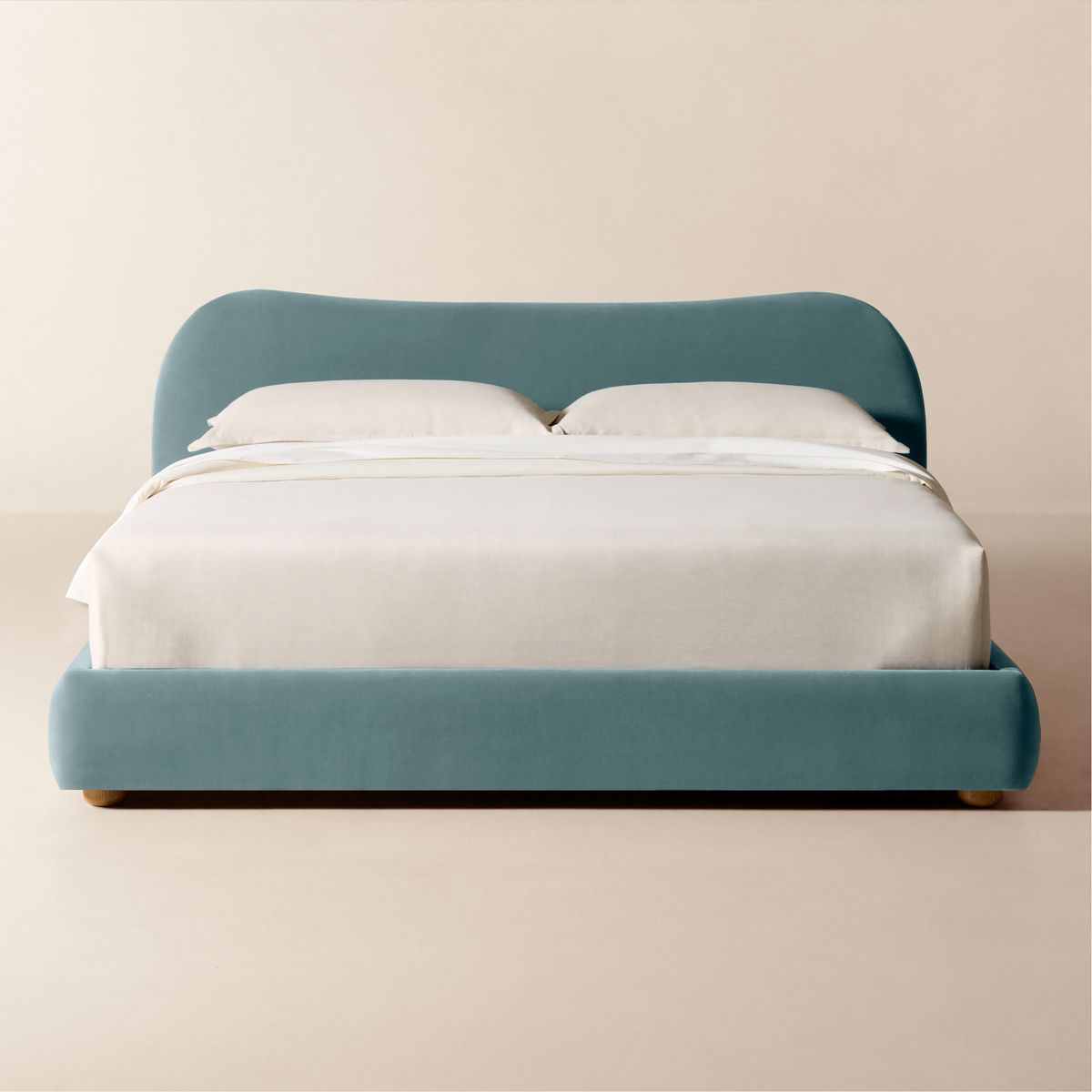Light blue velvet upholstered bed with curved silhouette